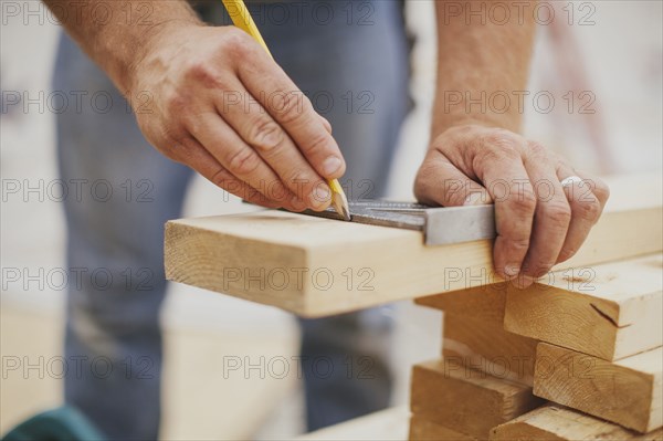 Caucasian construction worker marking wood planks