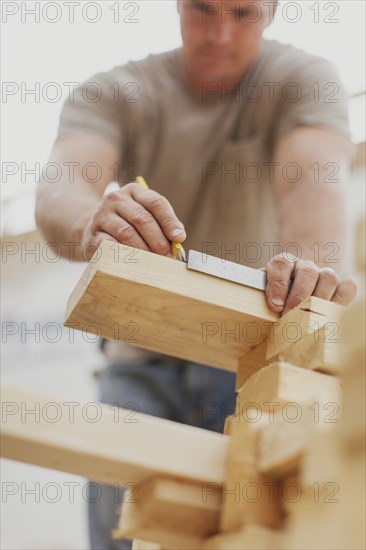 Caucasian construction worker marking wood planks