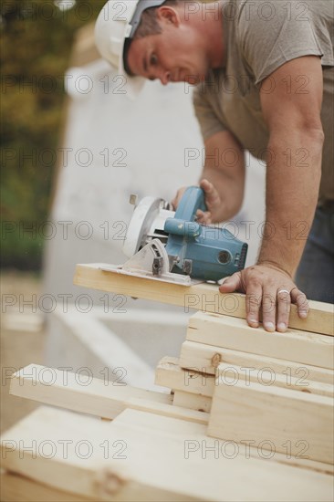 Caucasian construction worker sawing wood planks