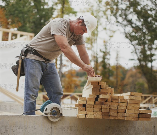 Caucasian construction worker marking wood planks