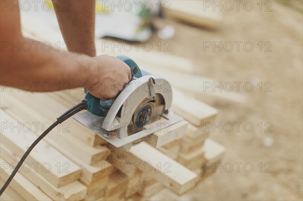 Caucasian construction worker sawing wood planks