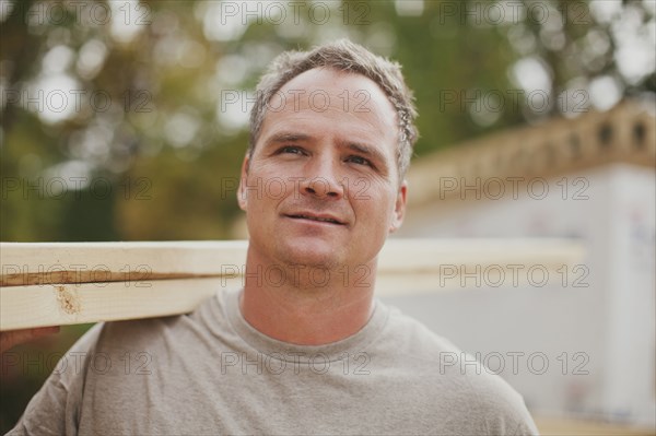 Caucasian construction worker carrying wood planks