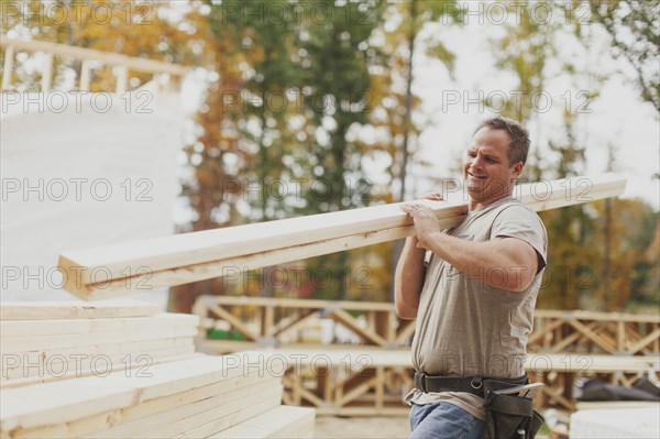 Caucasian construction worker carrying wood planks