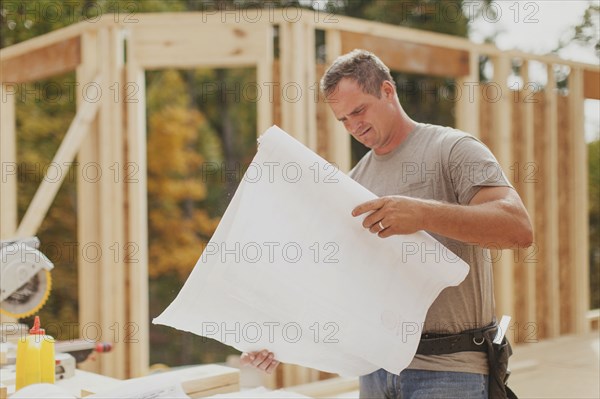 Caucasian construction worker reading blueprints on site