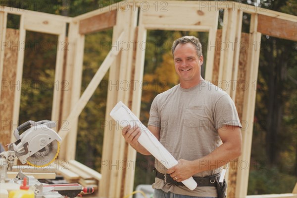 Caucasian construction worker holding blueprints on site