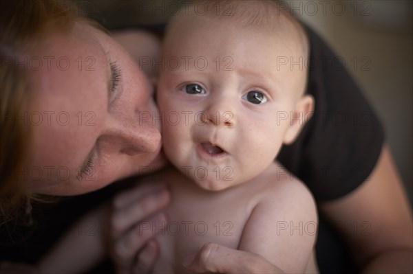 Caucasian mother kissing baby's cheek