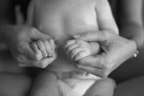 Caucasian mother holding baby's hands