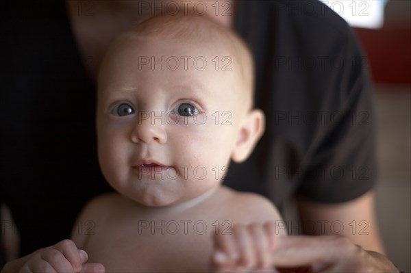 Caucasian mother holding baby's hands