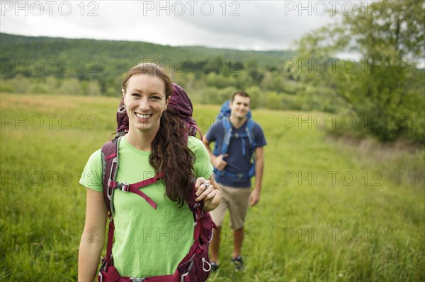 Caucasian couple hiking in rural field