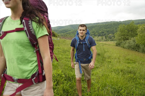 Caucasian couple hiking in rural field