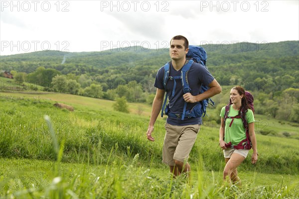 Caucasian couple hiking in rural field