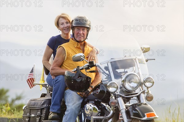 Older Caucasian couple smiling on motorcycle