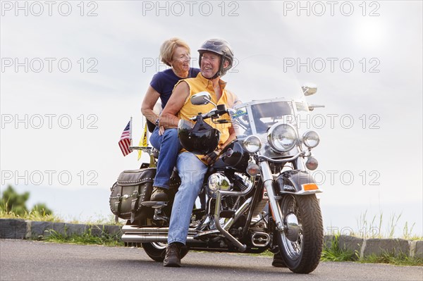 Older Caucasian couple smiling on motorcycle