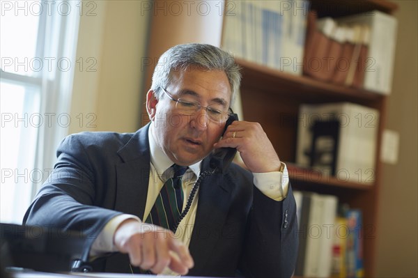 Mixed race businessman talking on telephone in office