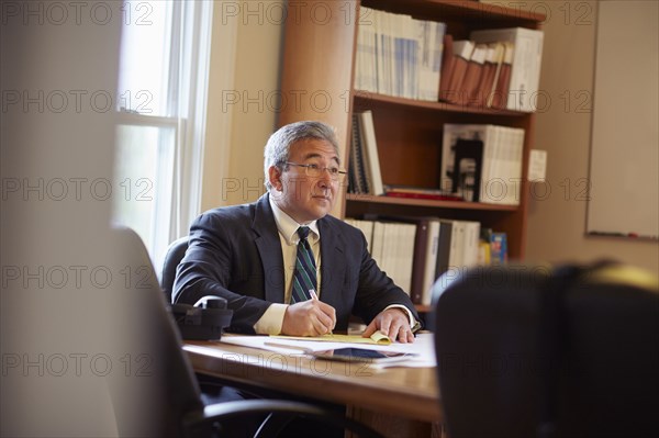 Mixed race businessman writing at desk in office