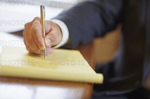 Mixed race businessman writing on notepad at desk