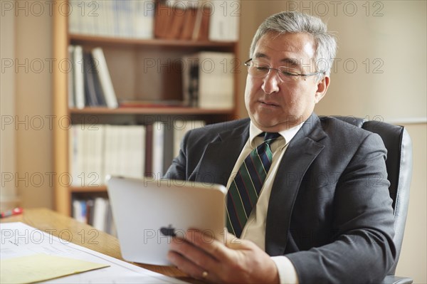 Mixed race businessman using digital tablet at desk in office