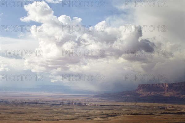 Puffy clouds rolling over rock formations in desert landscape