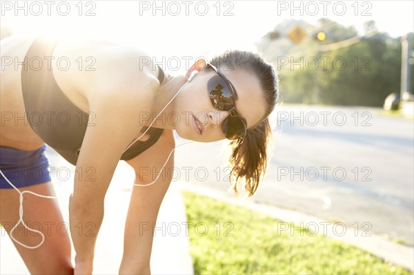 Caucasian runner stretching on sidewalk