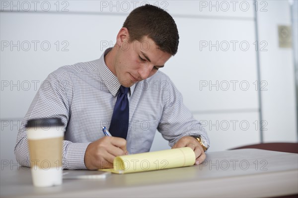 Caucasian businessman writing on notepad in office