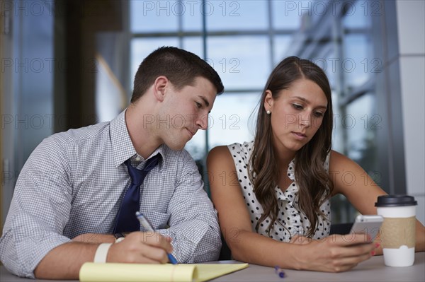 Business people using cell phone in office meeting