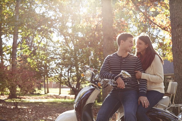 Couple sitting on scooter in park