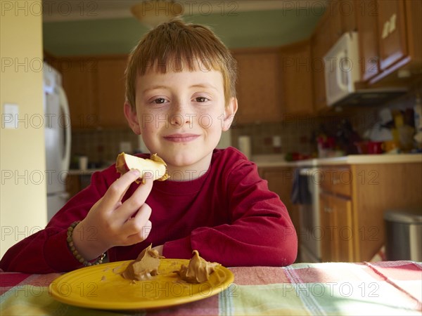 Caucasian boy eating apple with peanut butter snack