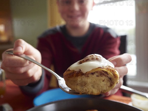 Caucasian boy showing cinnamon bun