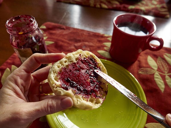 Caucasian boy spreading jam on english muffin