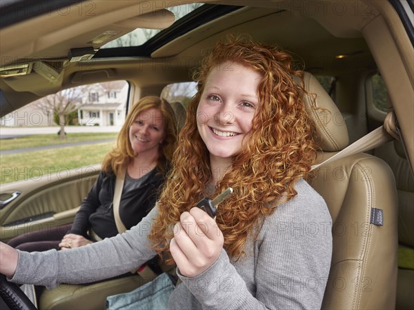 Caucasian teenage girl showing key with mother in car