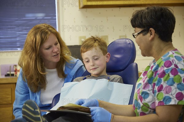 Pediatric dentist talking to patient and mother