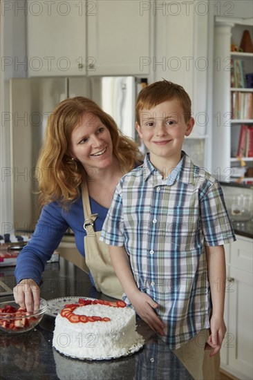 Caucasian mother and son decorating cake in kitchen