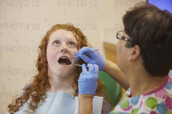 Pediatric dentist examining teeth of teenage patient