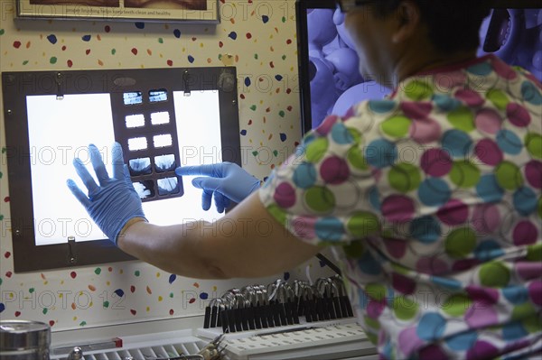 Pediatric dentist examining x-rays in office