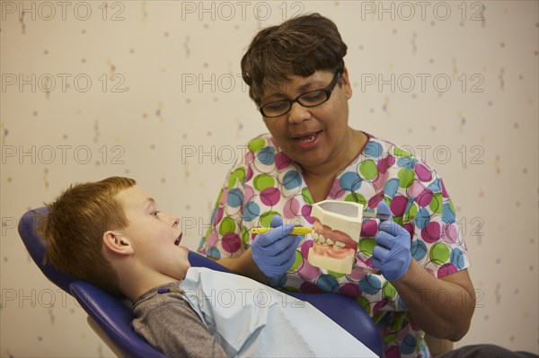 Pediatric dentist showing model teeth to patient in office