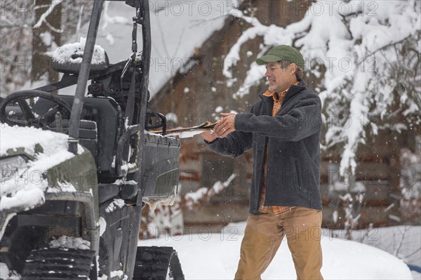 Mixed race man standing near snow vehicle