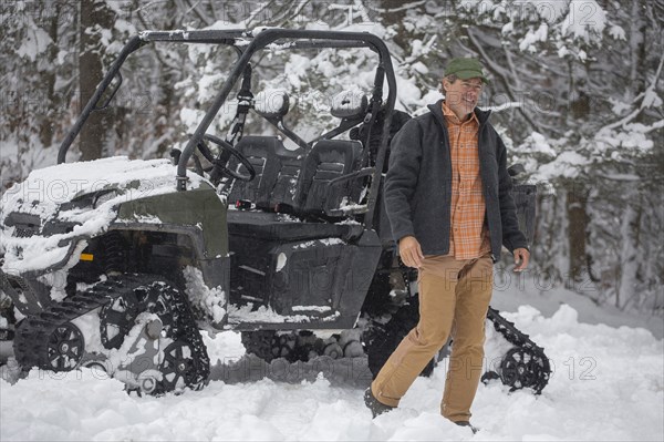 Mixed race man walking near snow vehicle in snow