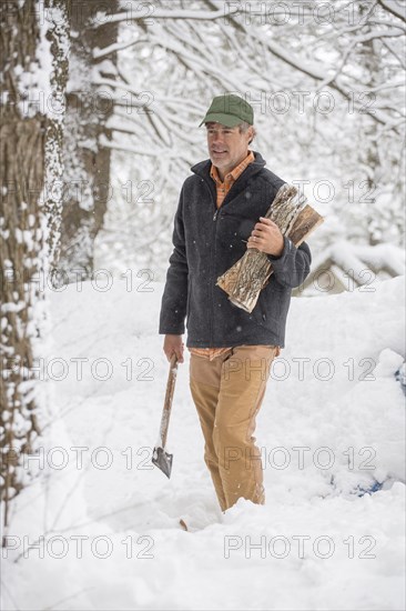 Mixed race man carrying firewood in snowy forest