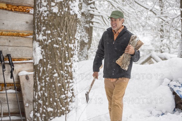 Mixed race man carrying firewood in snow