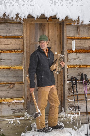 Mixed race man carrying firewood near snowy shed