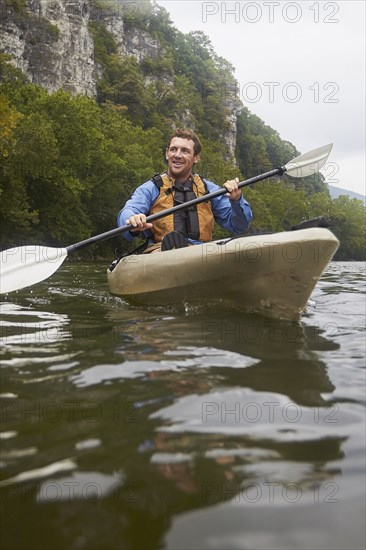 Caucasian man paddling kayak on remote river