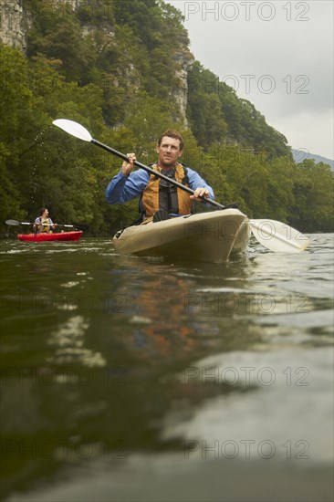 Caucasian man paddling kayak on remote river