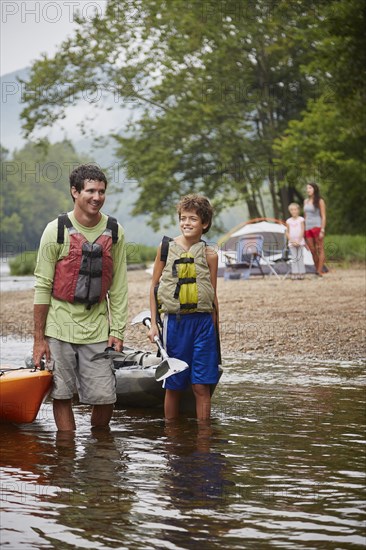 Father and son pulling kayaks in remote river