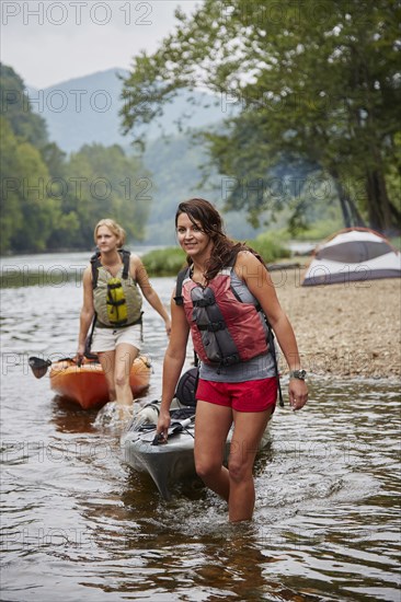Women pulling kayaks in remote river