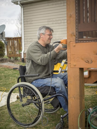 Caucasian paraplegic man wood working in backyard