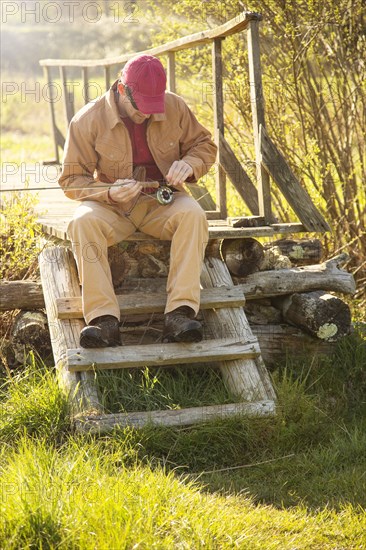 Caucasian man loading fishing pole on steps