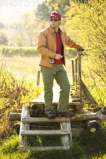 Caucasian man holding fishing pole on steps