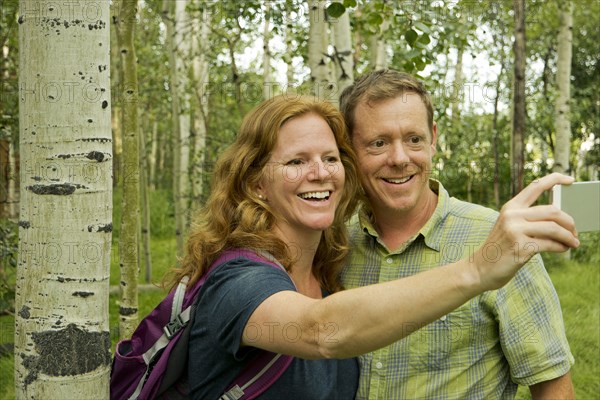Caucasian couple taking self-portrait in forest