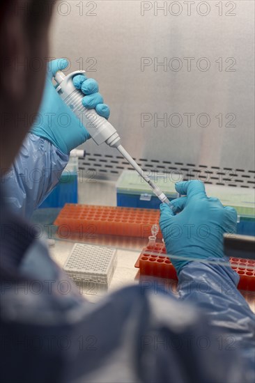 Mixed race scientist pipetting solution into test tubes in lab