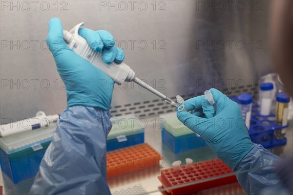 Mixed race scientist pipetting solution into test tubes in lab